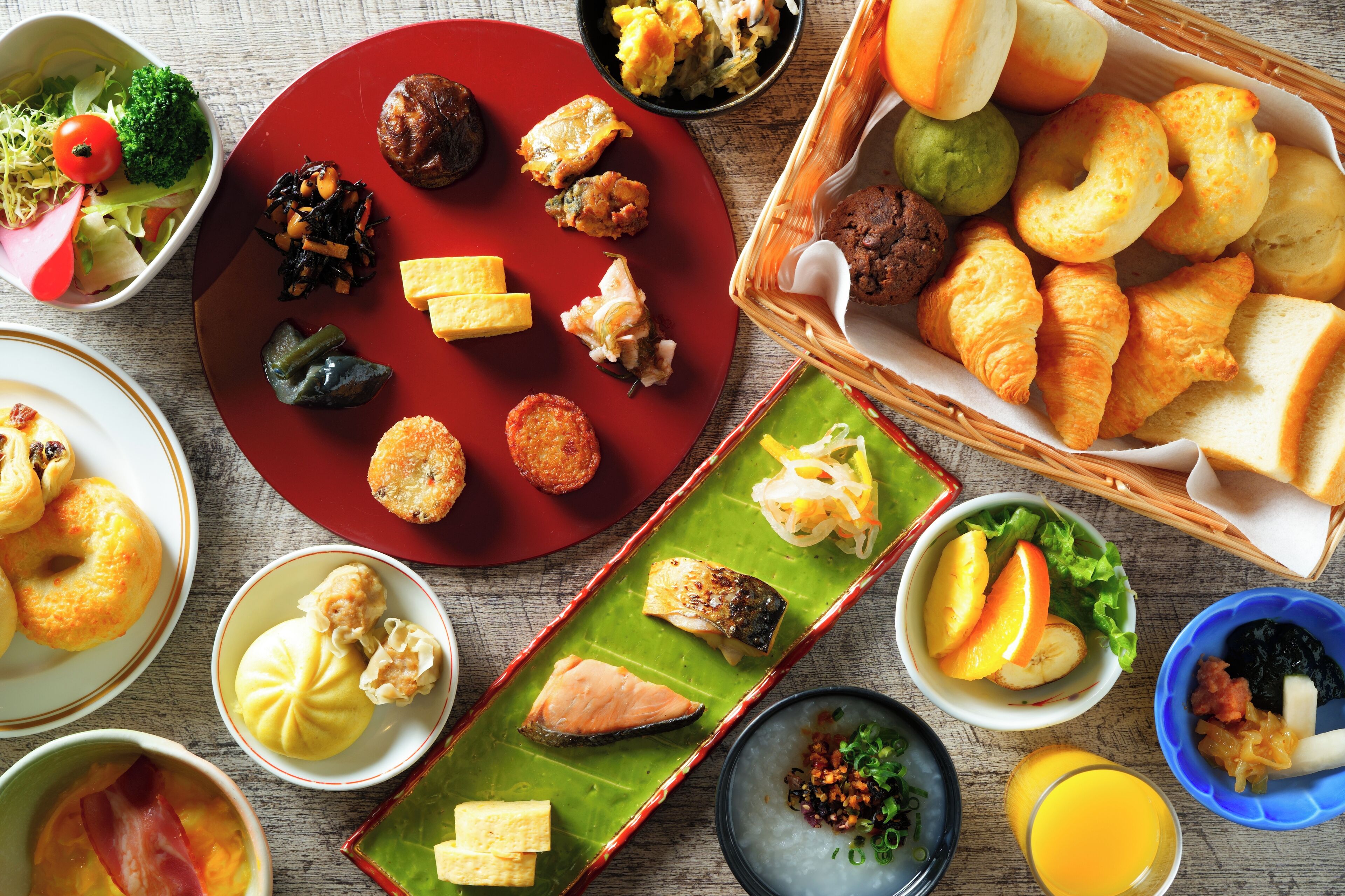 Une variété de plats, notamment des sushis, des sashimis et des pâtisseries, présentés sur une table en bois.