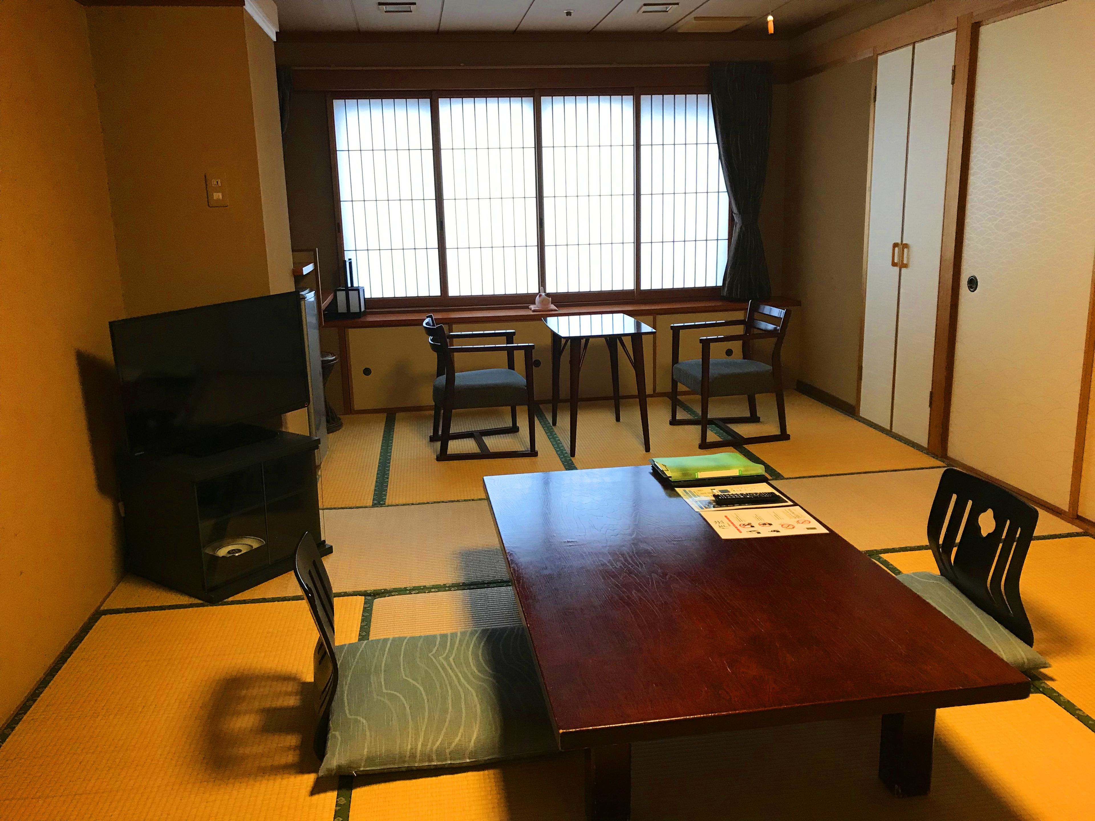 Een traditionele Japanse kamer met tatami vloerbedekking, een lage tafel en schuifdeuren.