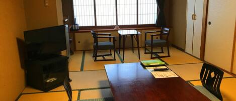 Een traditionele Japanse kamer met tatami vloerbedekking, een lage tafel en schuifdeuren.