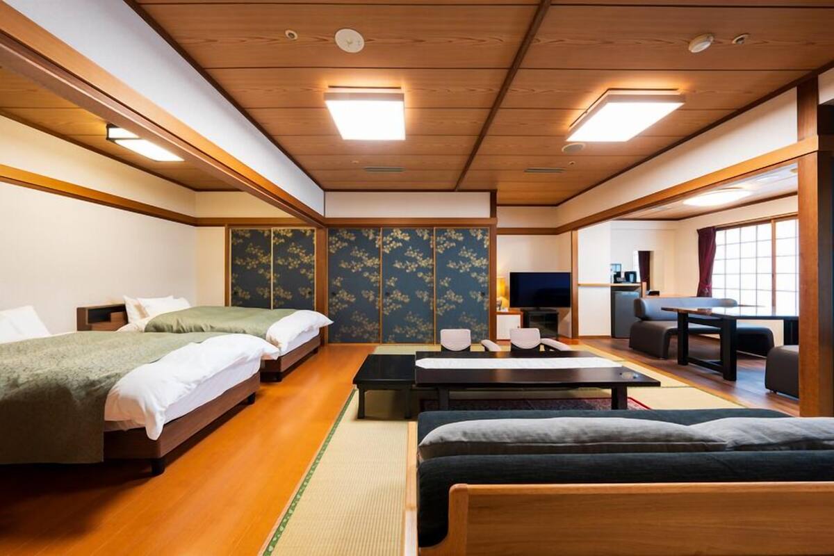 A traditional Japanese-style room with tatami flooring, a futon bed, a low table, and a television.