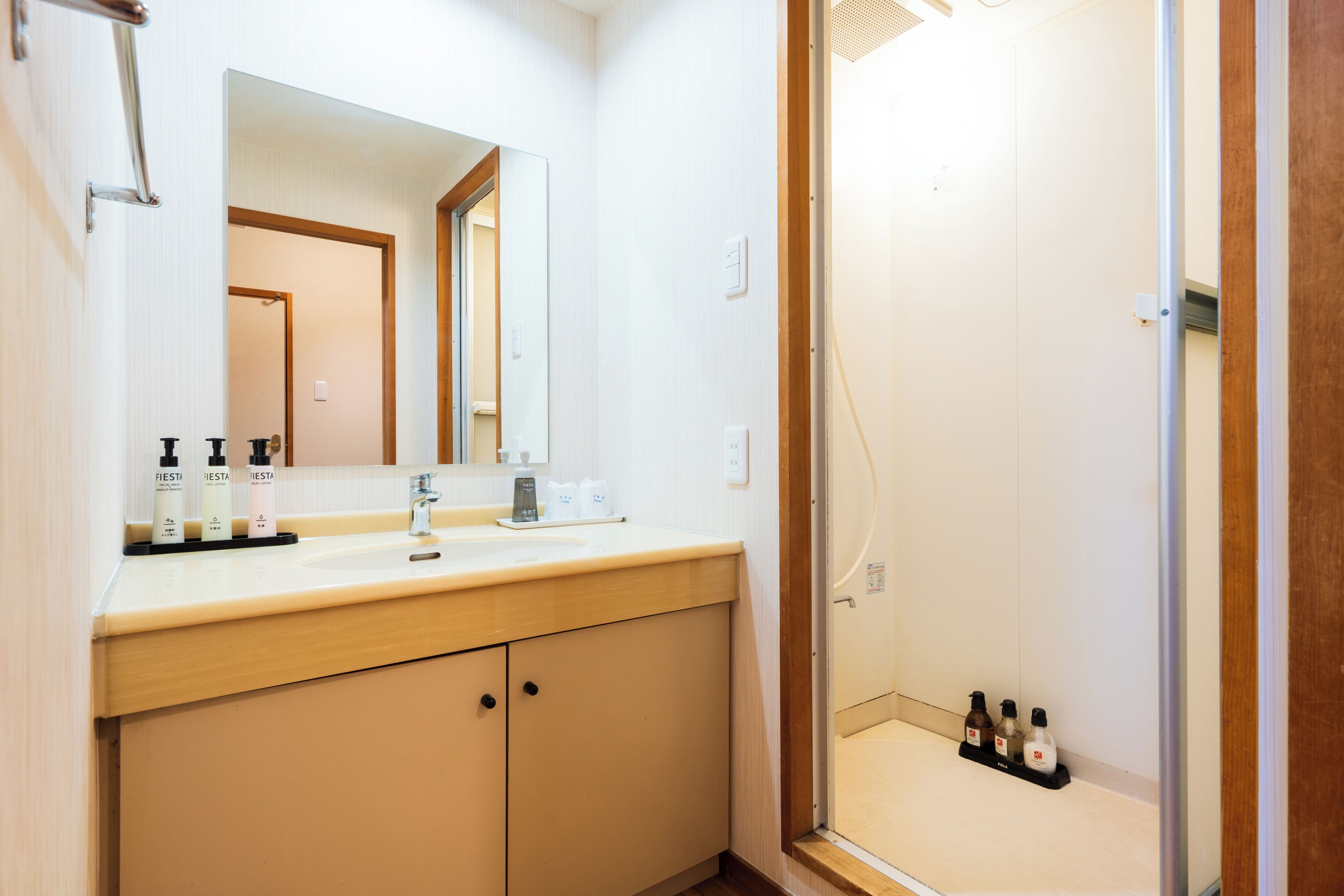 A bathroom with a sink, mirror, and shower area.