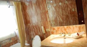 Un baño con pared de mármol, un lavabo y un inodoro.