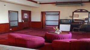 A hotel room with a large bed, a desk with a computer, a television, and a small table with flowers.