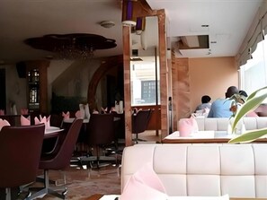 Un restaurante con diferentes opciones de asientos, incluyendo mesas y un área con sofás.
