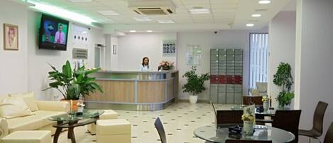 A reception area with a counter, seating, and a television screen.