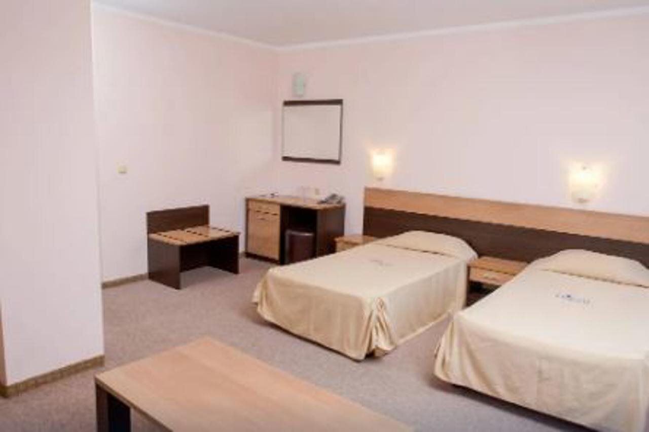 Una habitación de hotel con dos camas individuales, una mesita de noche, un escritorio y una silla.