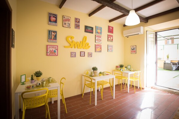 Un espace repas avec des chaises et des tables jaunes, décoré de différents éléments artistiques muraux sur le thème de la nourriture.