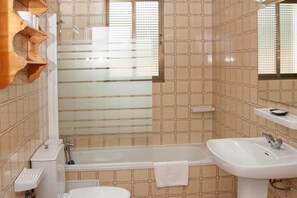 A bathroom with a bathtub, a sink, and a mirror.