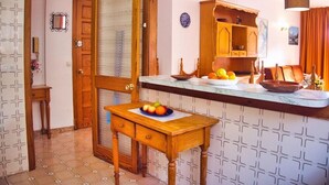 A kitchen with a wooden table, a fruit bowl, and a cabinet. - Bon Aire Apartamentos (Calvia)