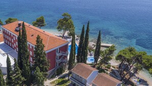 A coastal hotel with a red building, a swimming pool, and clear blue sea views. - Bellevue Maradiso Casa by Aminess (Orebic)