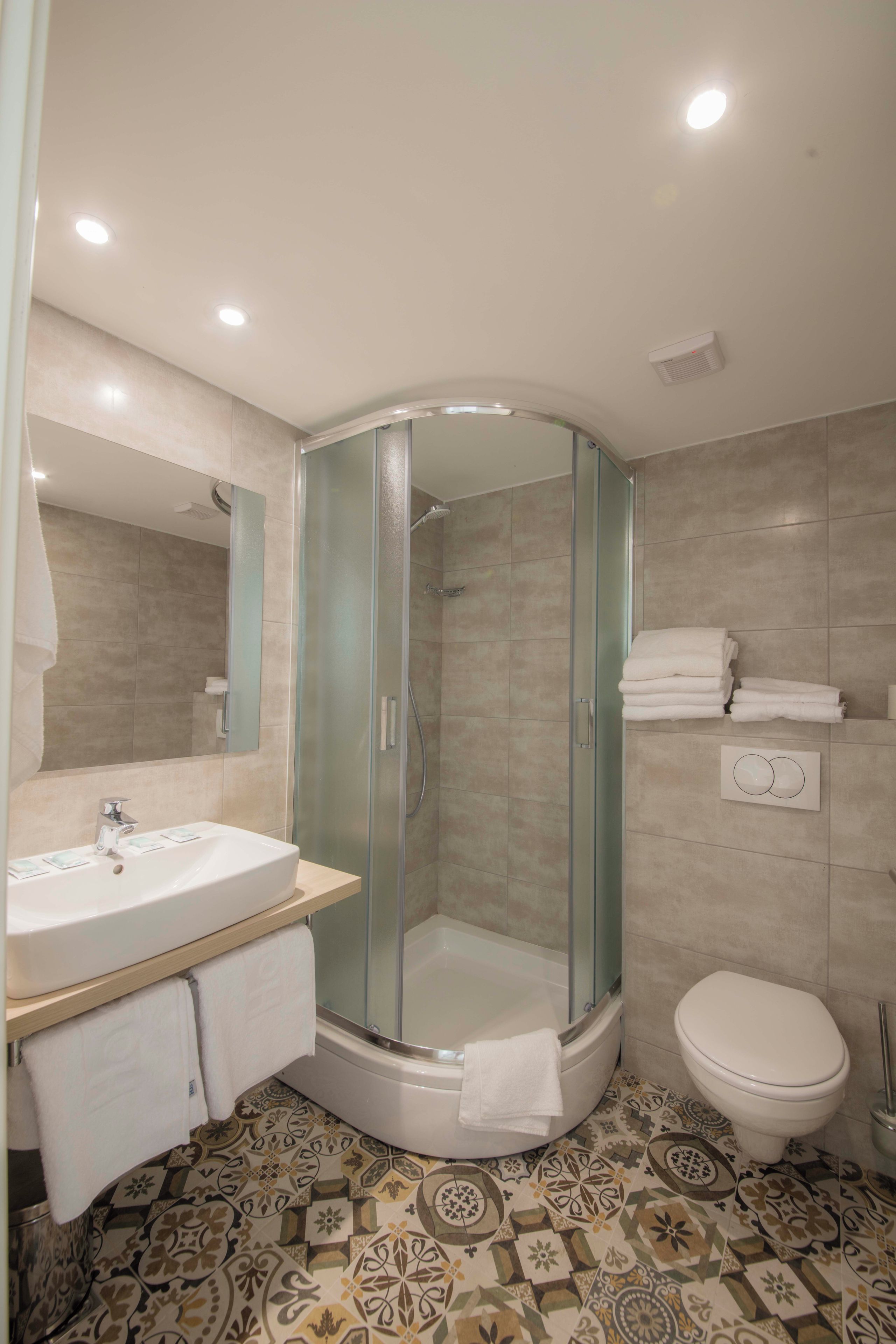 A bathroom with a glass-enclosed shower, a sink, and a toilet.