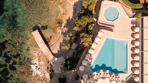 An aerial view of a resort with a large swimming pool, sun loungers, and a landscaped area with trees and a stone pathway. - Bellevue Maradiso Casa by Aminess (Orebic)