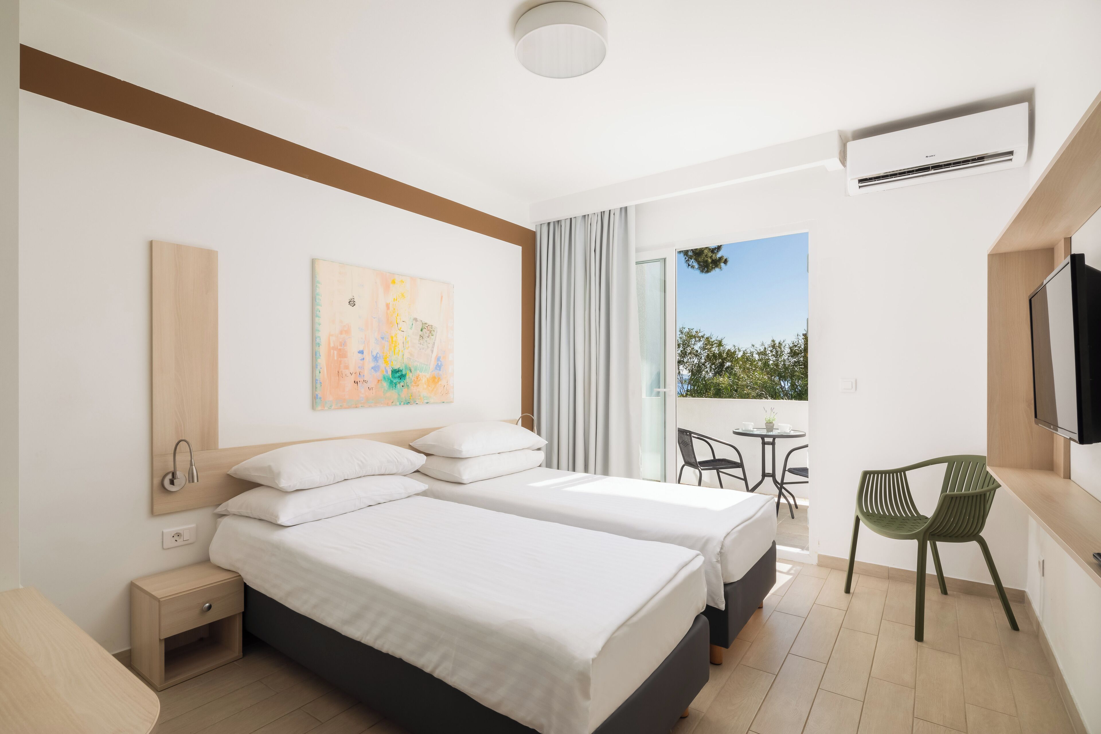 Habitación de hotel moderna con dos camas, un escritorio, una silla y un balcón con vistas.