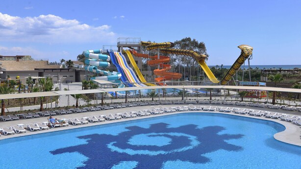Une piscine avec un grand toboggan et un espace de détente équipé de chaises longues.