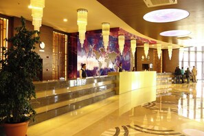 A hotel lobby with a reception desk, a large world map mural, and a potted plant. - Sunmelia Beach Resort Hotel & SPA (Manavgat)