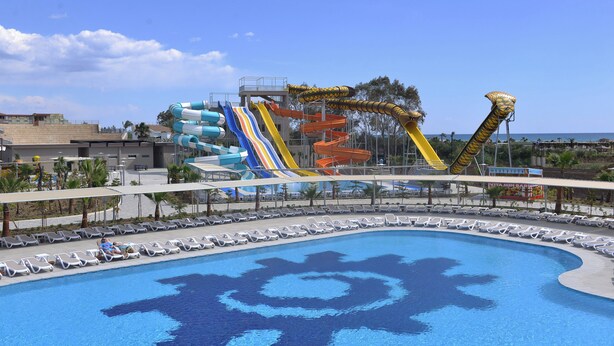 Een waterpark met meerdere glijbanen en een zwembad met een tandwielmotief.