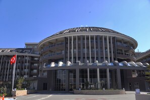 A modern multi-story building with a curved facade, large windows, and balconies. - Sunmelia Beach Resort Hotel & SPA (Manavgat)