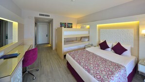 Een hotelkamer met een stapelbed, een bureau met stoel, een nachtkastje met lamp en een telefoon.