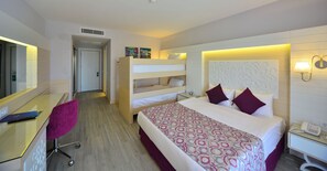 Quarto de hotel com cama de solteiro, escrivaninha com cadeira, mesa de cabeceira com abajur e telefone.