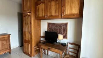 Un espace de vie compact doté de meubles en bois, d’une petite table à manger, d’un téléviseur et d’un fauteuil rembourré.