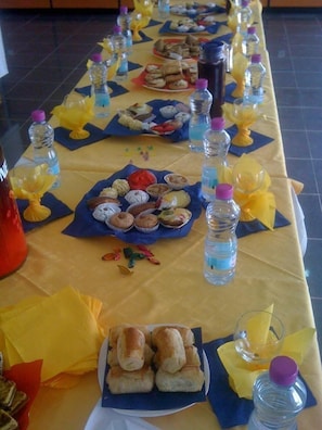 A long table with various food items and water bottles. - Frantz Fanon (Setif)