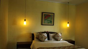 A hotel room with a bed, two bedside tables, and two hanging light fixtures.