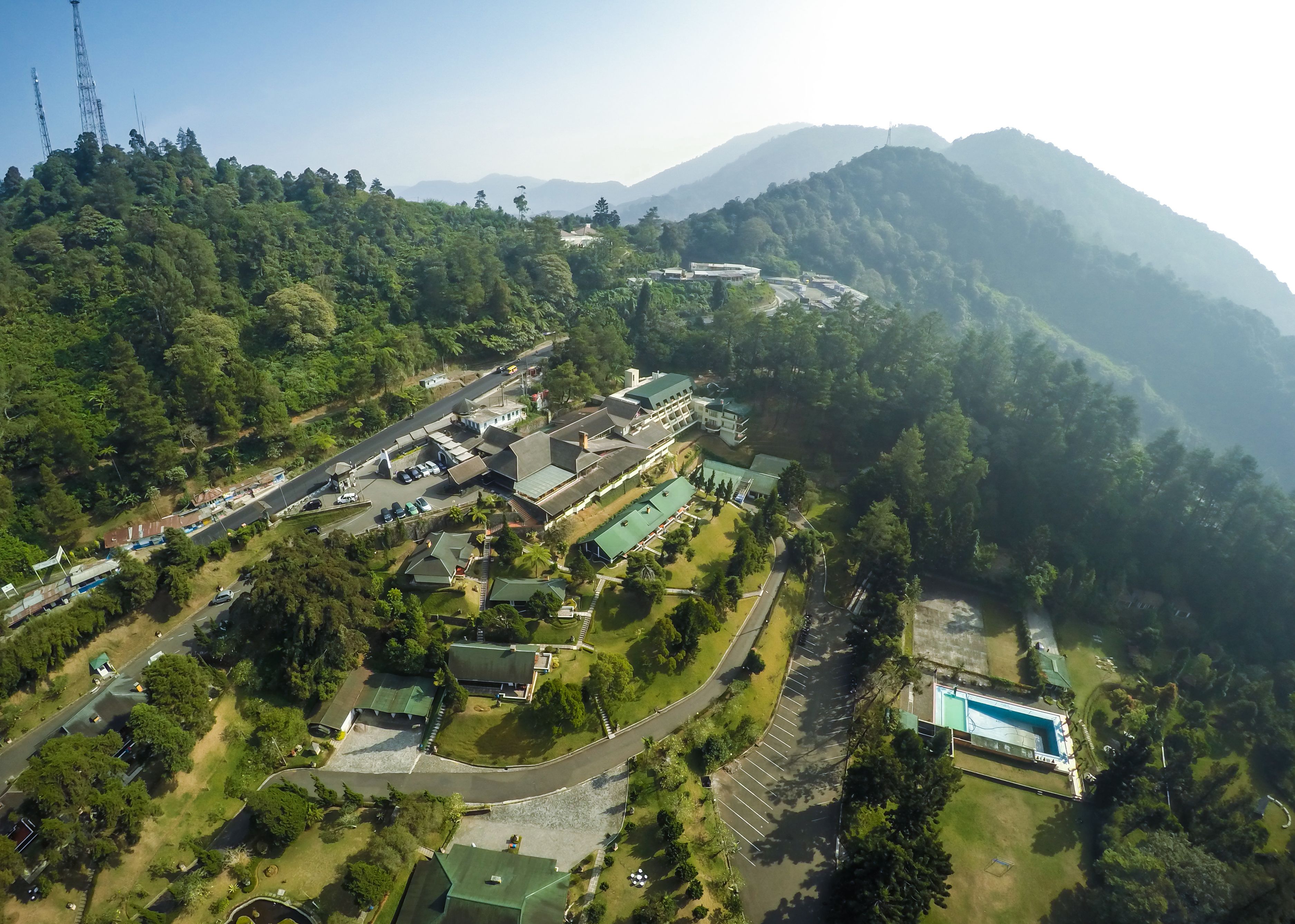 An aerial view of a resort with multiple buildings, a swimming pool, and a road winding through the property.