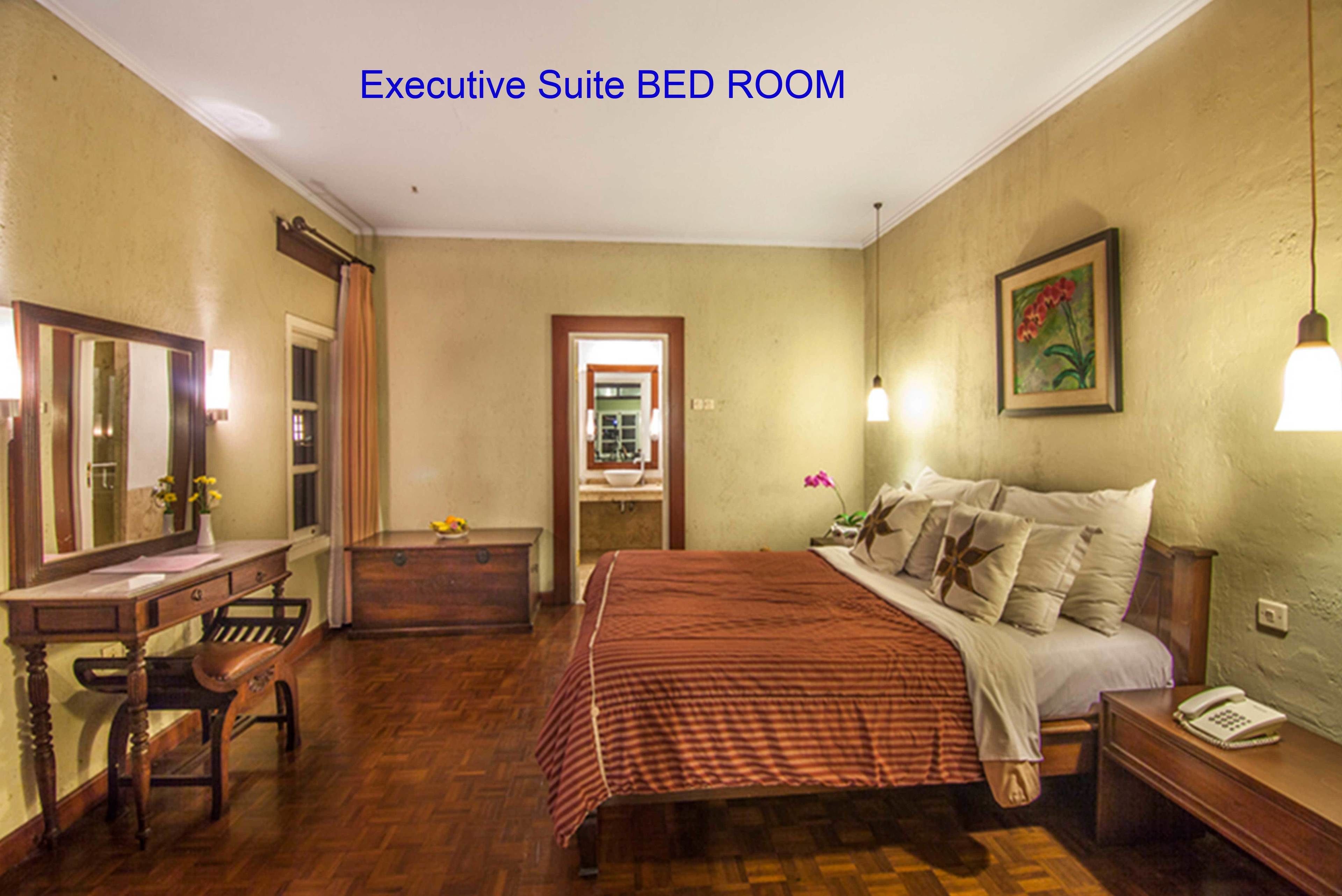 An executive suite bedroom with a large bed, a desk, and a chair.