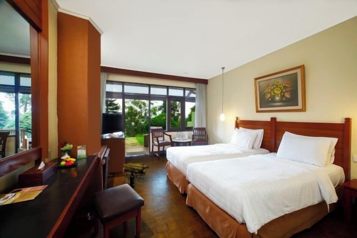 Habitación de hotel con dos camas, un escritorio y un comedor con sillas.