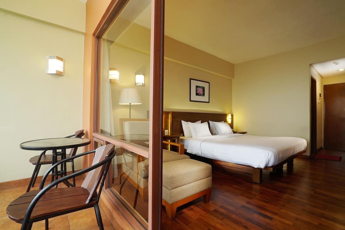 A hotel room with a bed, a small table, and a chair.