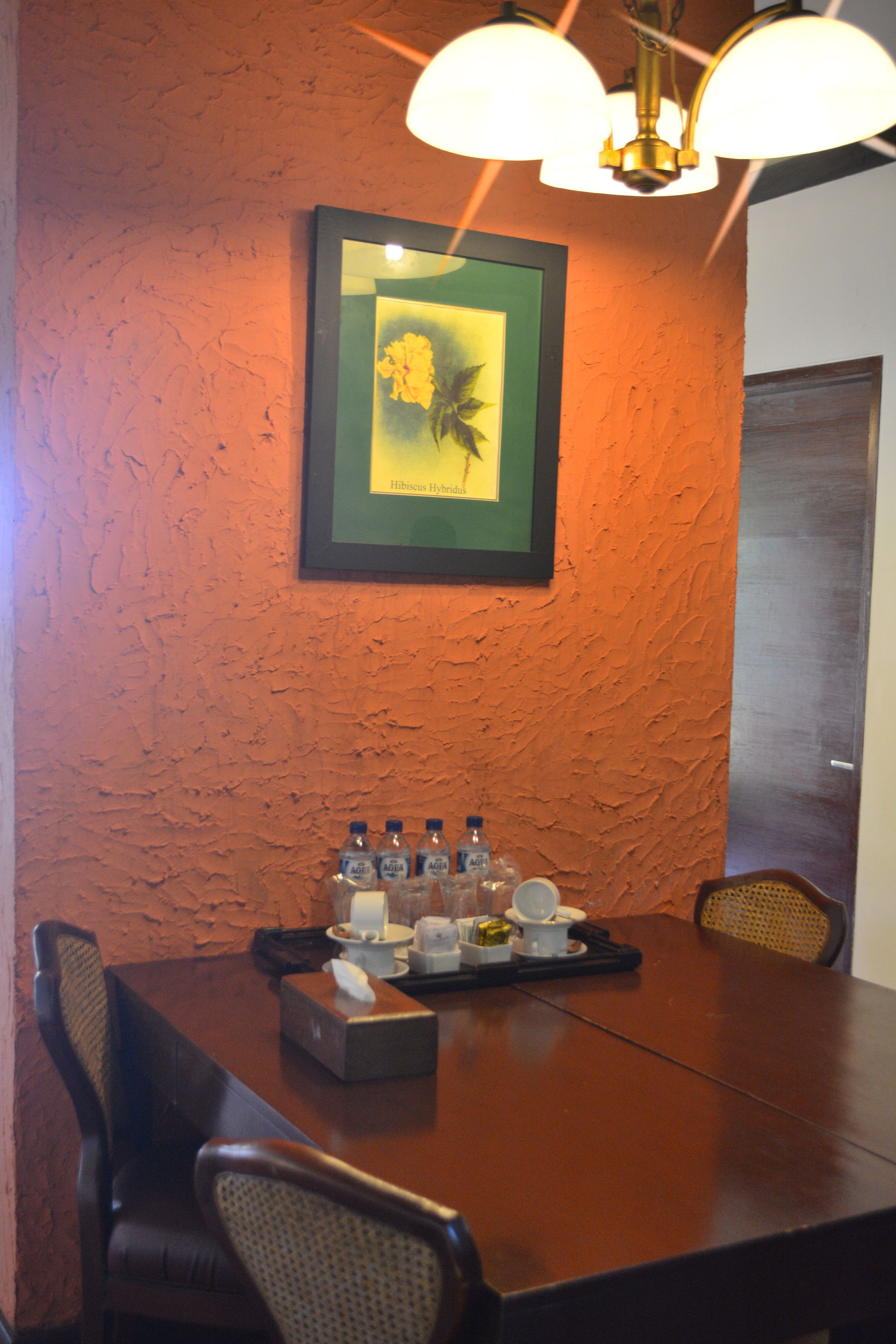 Un salón de conferencias con una mesa de madera, sillas, un cuadro en la pared y un dispensador de agua.
