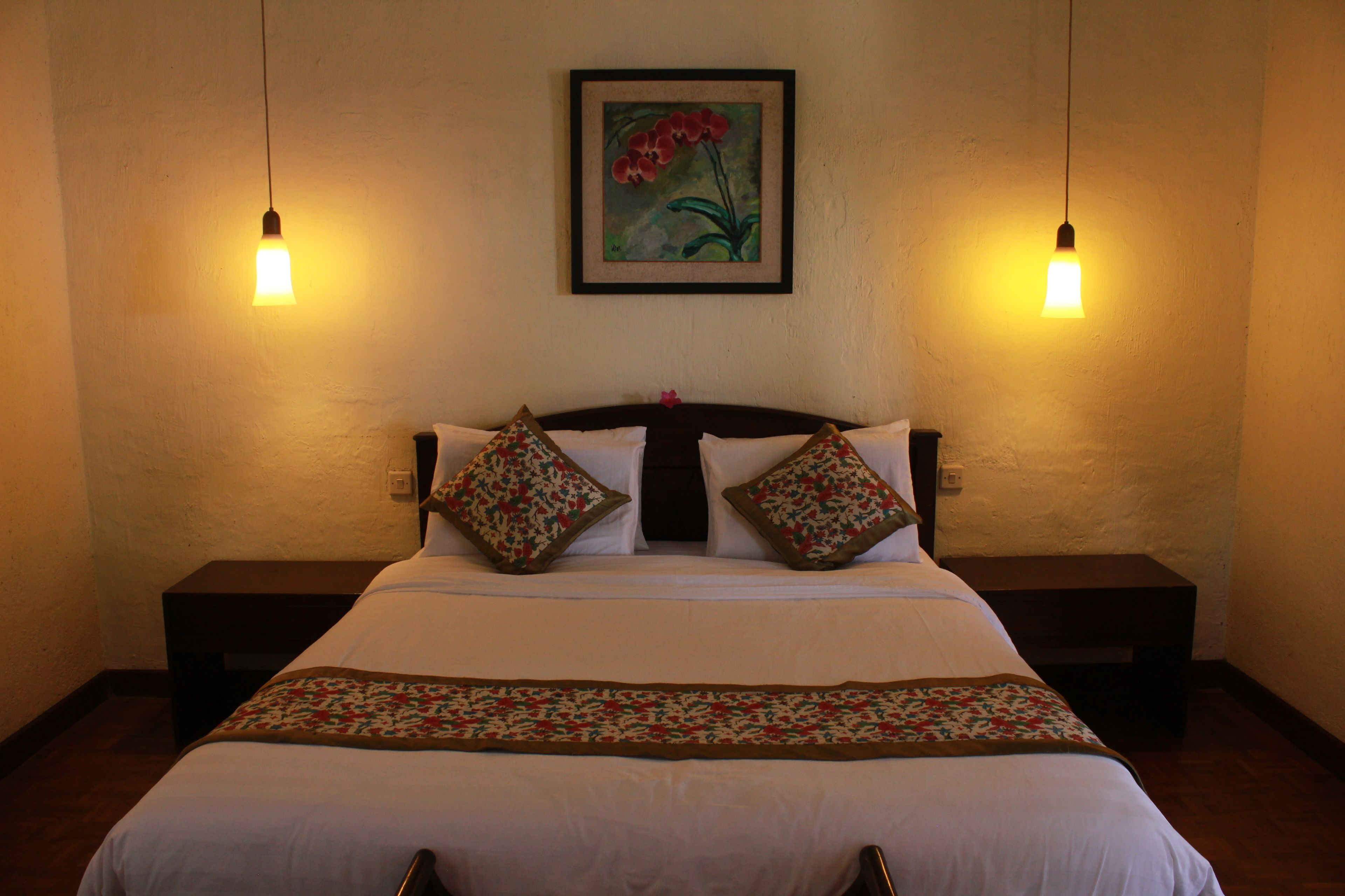A neatly made bed with floral-patterned pillows and a matching throw, flanked by two bedside tables with lamps.