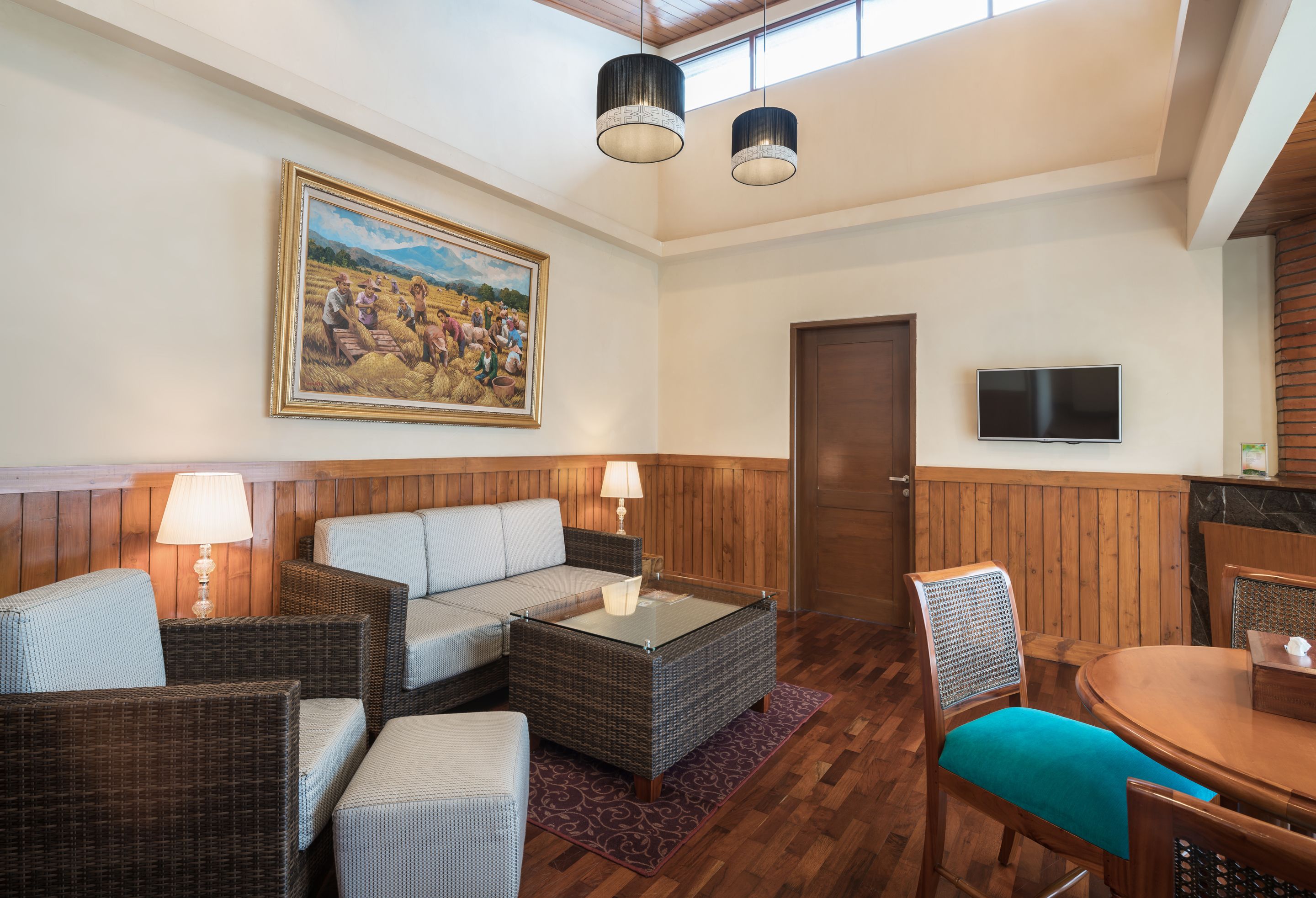 A room with wicker furniture, a television, and a painting on the wall.