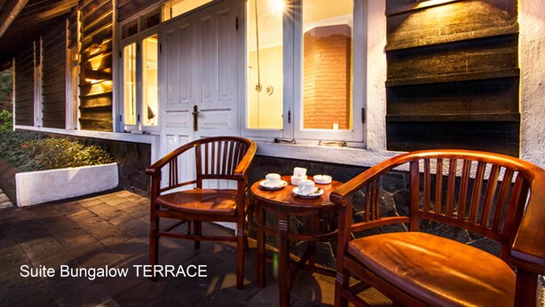 Une suite-bungalow dotée d’une terrasse aménagée avec des meubles en bois et un jardinière en pierre.
