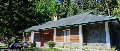 Una casa de dos pisos con fachada de piedra, techo verde y un pequeño porche.