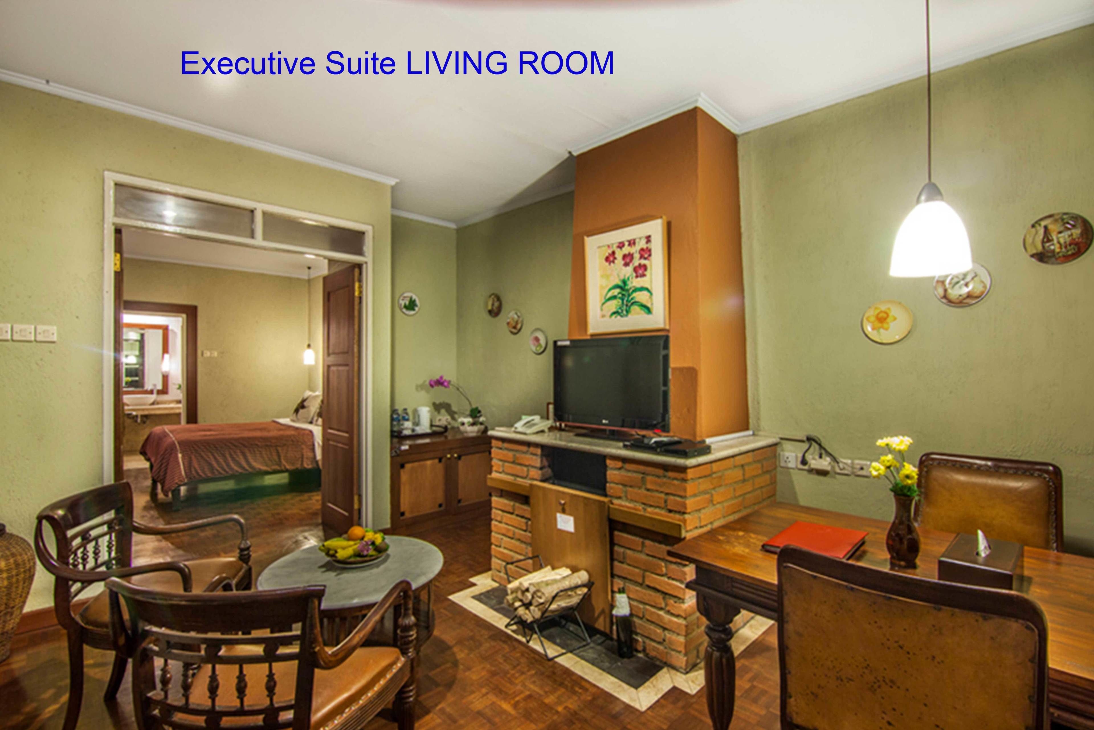 An executive suite living room with a dining area, a television, and a fireplace.