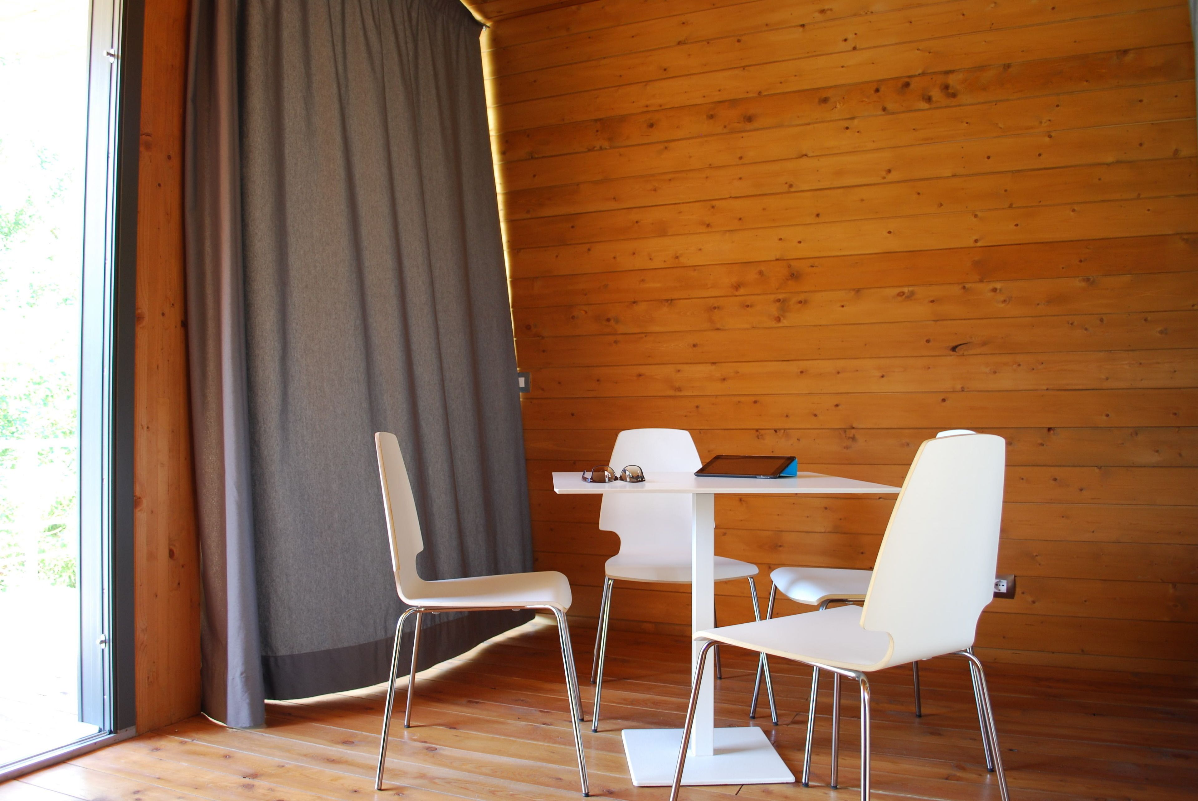 Ein Zimmer mit Holzwänden, einem weißen Tisch und vier weißen Stühlen.