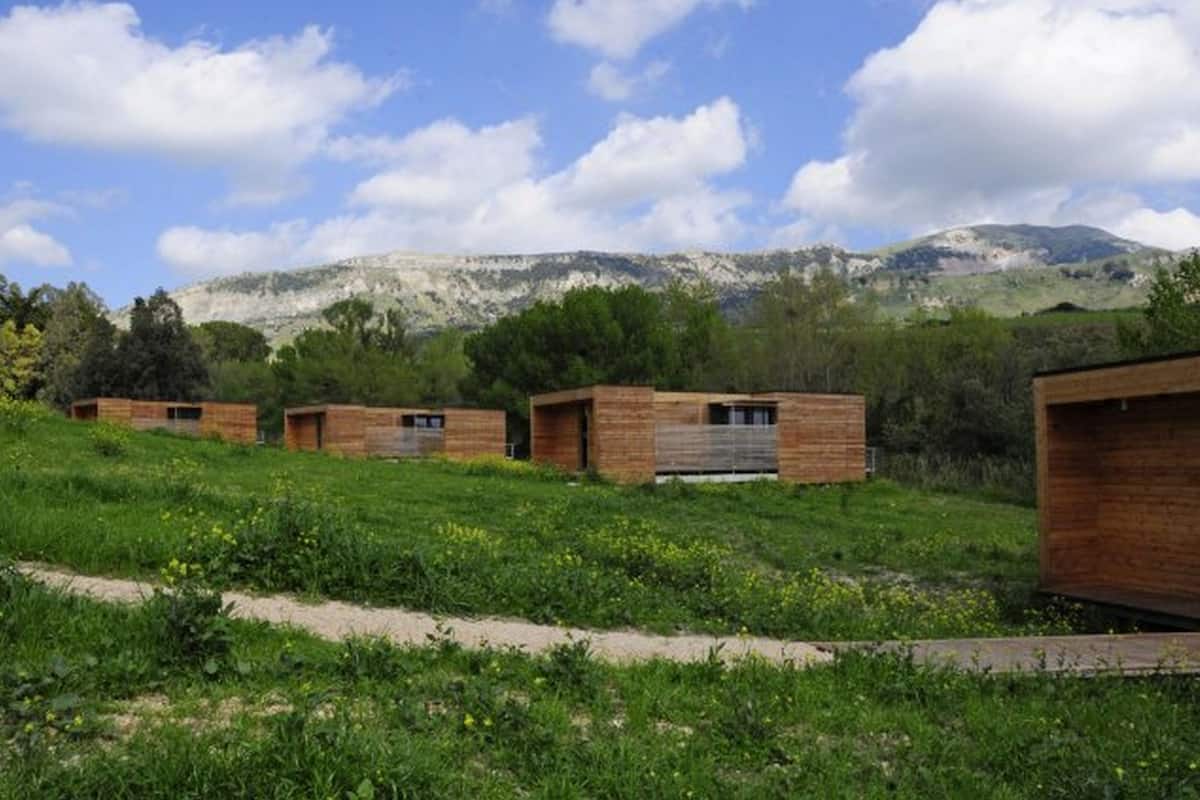 A row of wooden cabins with a mountain backdrop.