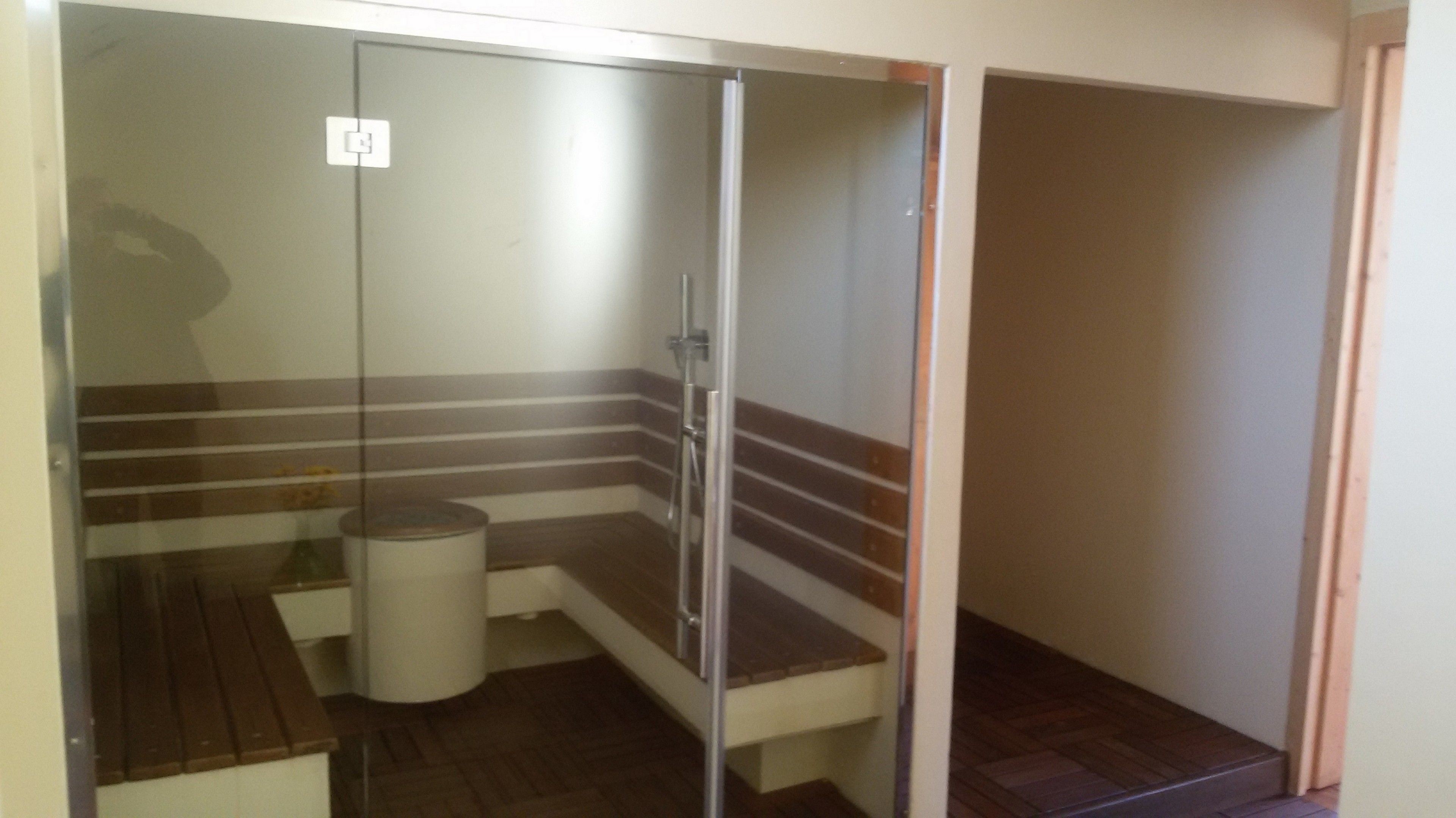 Un espacio de ducha pequeño y cerrado con un banco, un cubo de basura y un perchero para toallas.