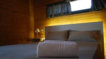 A cozy room with a bed, a nightstand, a lamp, and a window with curtains.