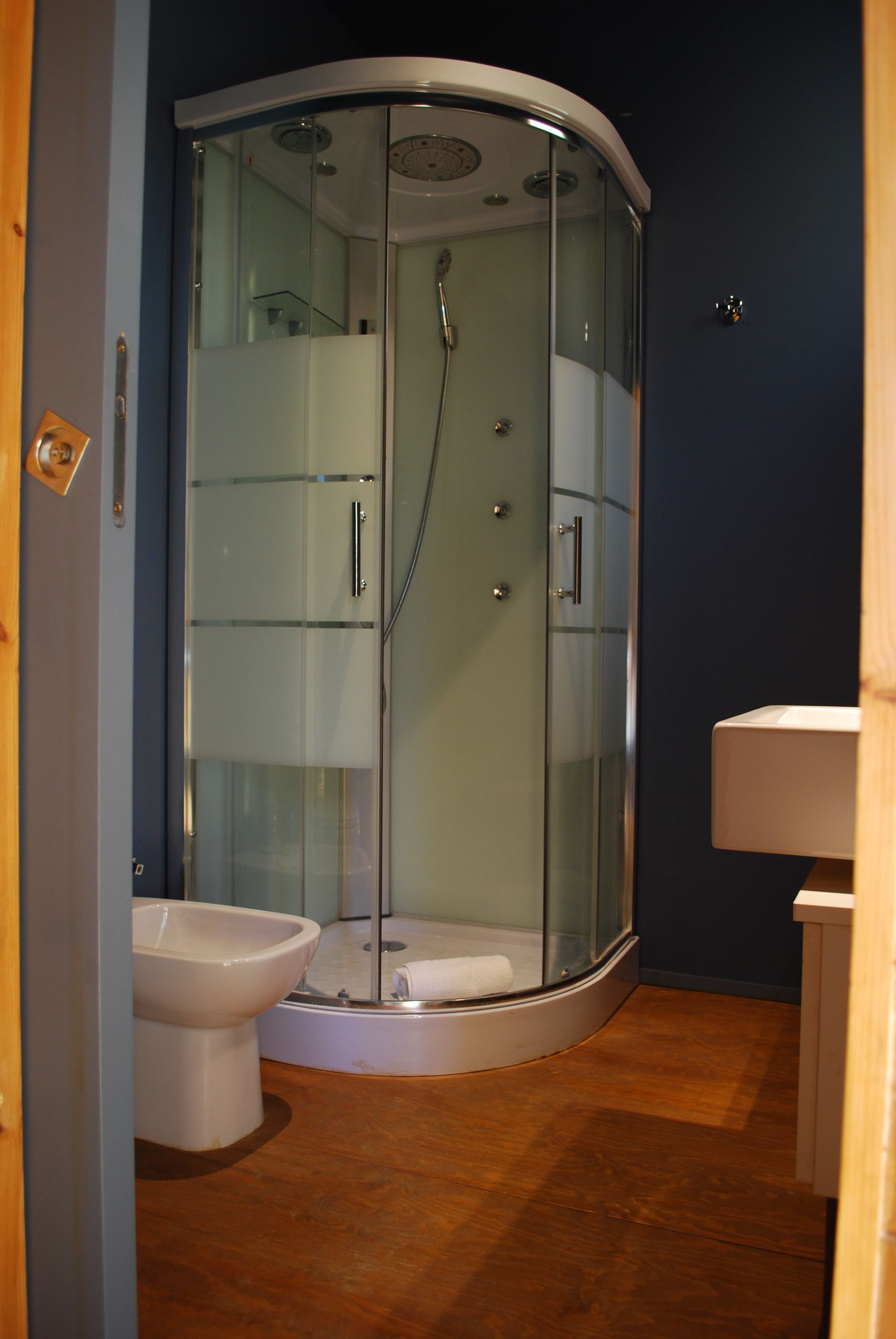 Un baño moderno con cabina de ducha de vidrio, inodoro y lavamanos.