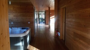Een houten blokhut met een hottub in het midden, houten wanden en een brandblusser op de vloer.