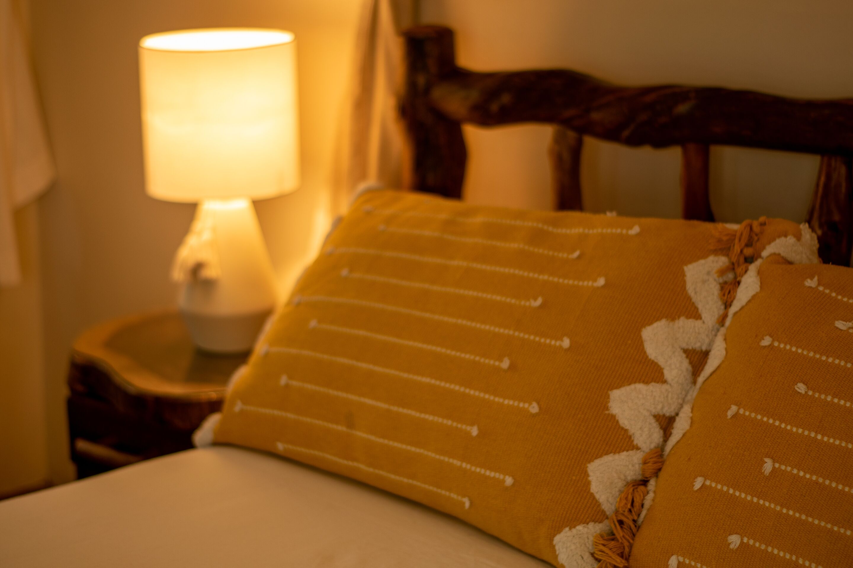 Una cama con un almohadón amarillo y un cabecero de madera.