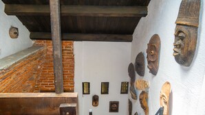 Una habitación con pared de ladrillo, vigas de madera y diversos artefactos culturales exhibidos.
