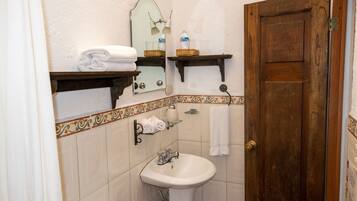 A bathroom with a sink, mirror, towel rack, and wooden door.