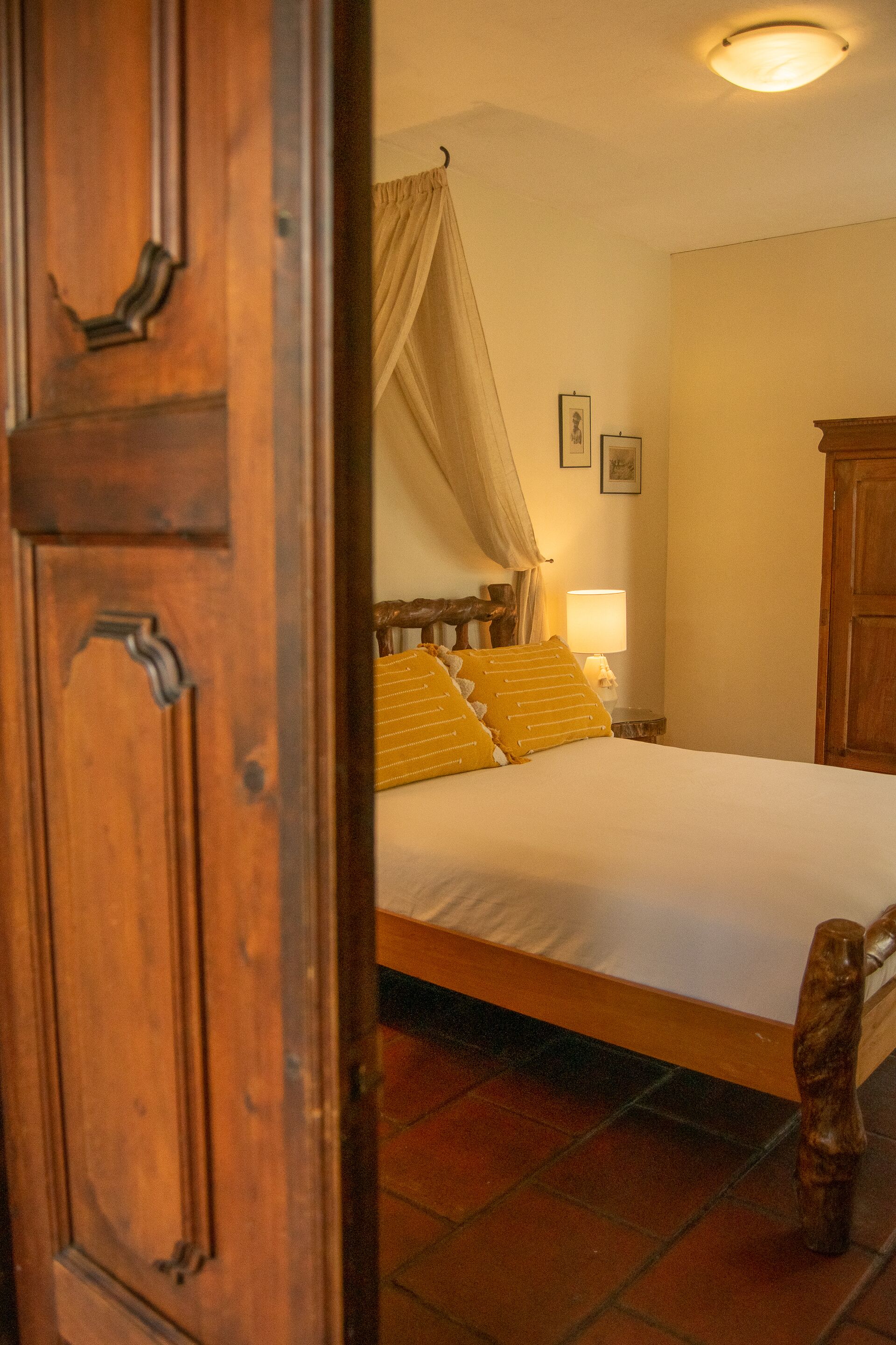 A bedroom with a wooden bed, a nightstand with a lamp, and a wooden wardrobe.