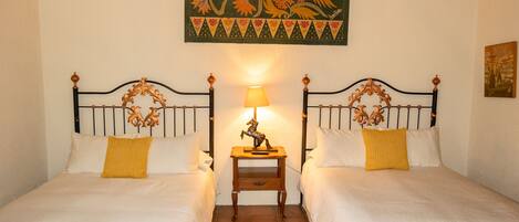 A hotel room with two beds, a nightstand with a lamp, and a decorative wall hanging.