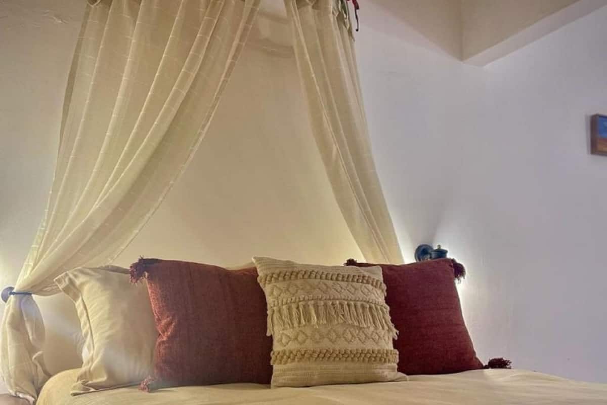 Una cama con dosel, dos almohadas y una mesita de noche.