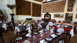 Un espace repas avec plusieurs tables dressées pour les repas, agrémenté de nappes traditionnelles et de meubles en bois.
