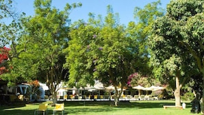 Un jardin luxuriant, agrémenté d’un espace extérieur avec des sièges et des parasols, entouré d’arbres et de verdure.